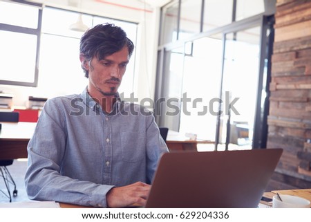 Mid-adult white man working in an office using laptop, close up