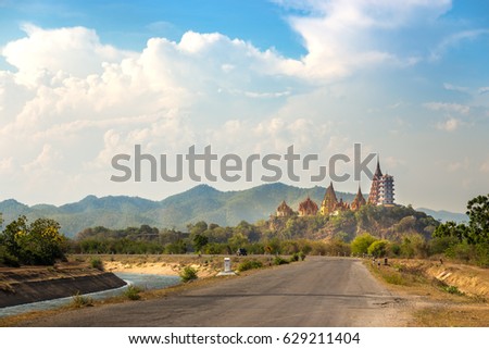 big Buddha temple, Wat Tham Suea, on mountain with view from country road and river side in Kanchanaburi Thailand