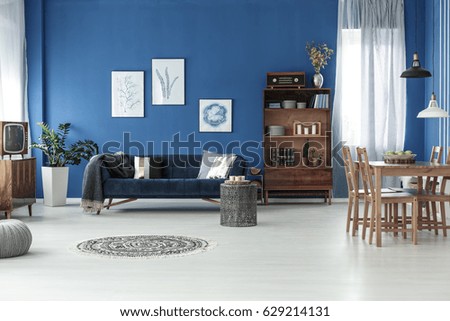 Spacious retro style living room with blue wall and wooden floor