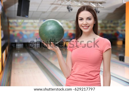 Young woman with ball in bowling club
