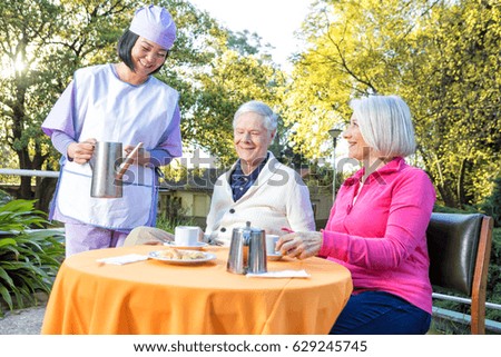 Elderly couple making breakfast outdoor served by asian nurse.