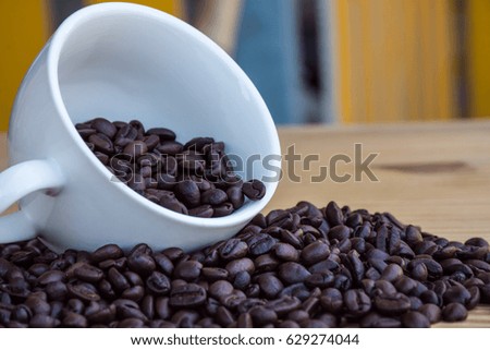 The coffee bean in white cup on the wood table. Horizontal picture