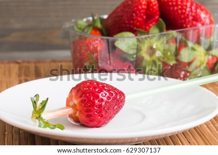 Strawberries in a transparent box on wooden background.