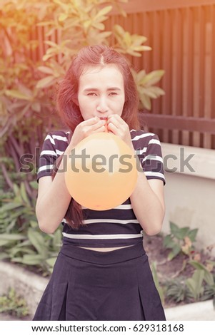 asia young girl is inflating balloon at outdoor background