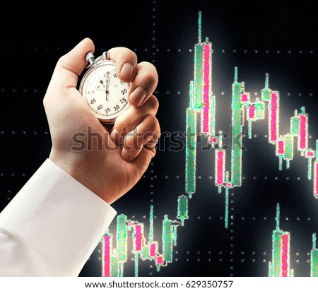 Candlestick chart graphic and stopwatch in male hand