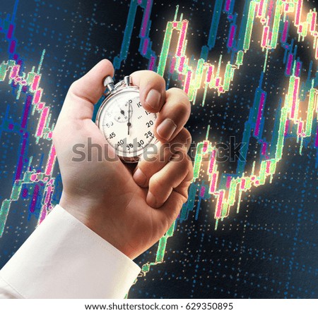 Candlestick chart graphic and stopwatch in male hand