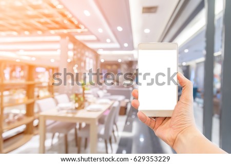 hand with smartphone with blur background image of shopping mall or department store with bokeh and people background usage concept
