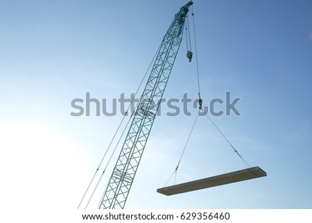 Crawler crane lifting precast concrete  hollow core slab for installation under the construction with blue sky 