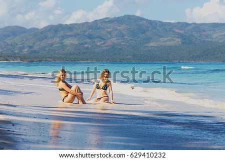 two pretty young girls in bikini relax on the beach
