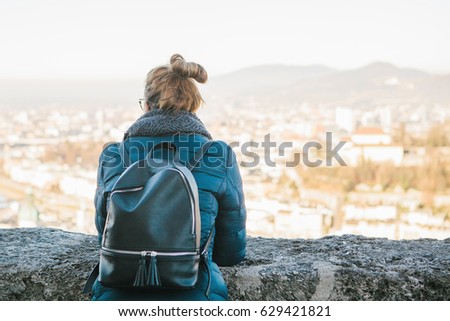 Young woman tourist on the viewpoint, admiring the view of the mountains "Alps" and the city of Salzburg in Austria. Travel, vacation, tourism, attractions.