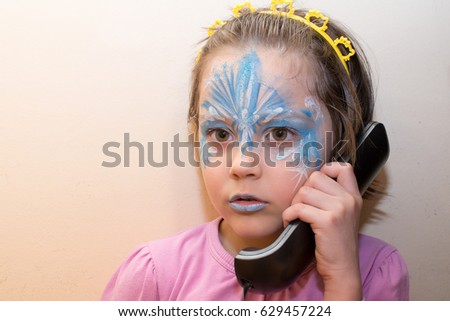 Portrait of little girl with face painting talking on the old phone