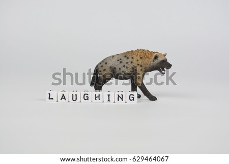A spotted hyena toy stands behind the word "laughing" spelled out with letter beads. Hyenas are sometimes referred to as "laughing" because of the sound they make