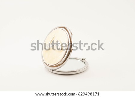 Open compact mirror in silver and cream with shoe picture in jewels from the back isolated and centered on white background