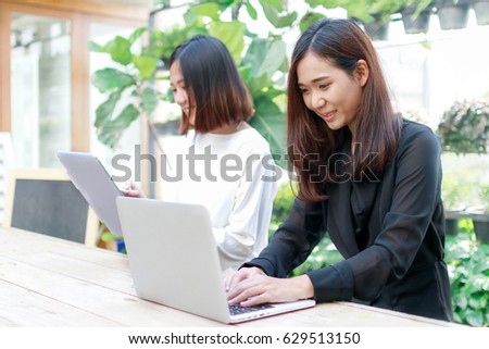 Two beautiful Asian girls using tablet and laptop in cafe,modern lifestyle with technology or working woman on casual business