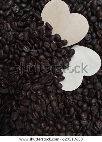 Closeup little hearts among coffee beans background,in vintage warm light tone,art style,grainy film design.