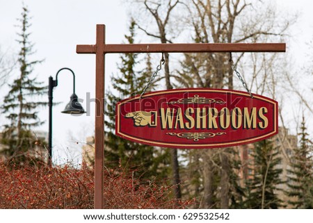 Old fashioned, stylish sign points the direction to public washrooms in a city park