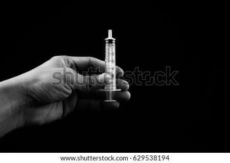 Hand holding a syringe isolated over black background