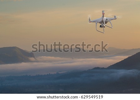UAV drone copter flying with digital camera.Drone with high resolution digital camera. Flying camera take a photo and video.The drone with professional camera takes pictures of the misty mountains.