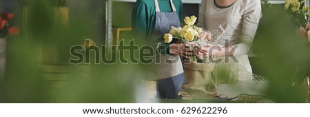 Two florists arranging pretty yellow flowers in bouquet
