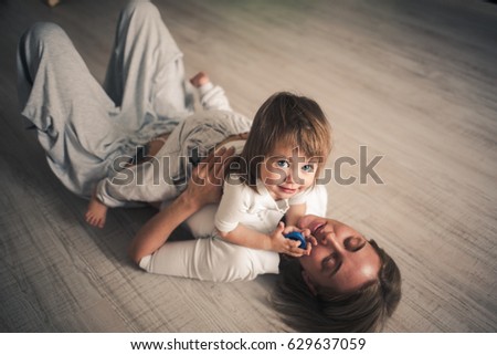 Beautiful young blond mother with her cute little daughter on the floor. Image with selective focus and toning.