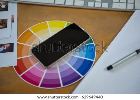 Close-up of mobile phone with color swatch on office desk