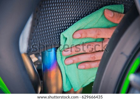 Hand with man cleaning motorcycle with green microfiber cloth 