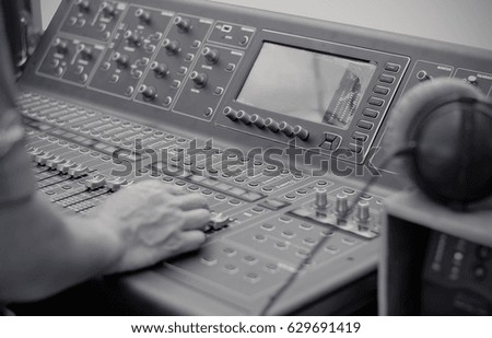 Hand Control of high-quality audio and equalizer volume on sound mixing console with headphones ,selective focus, black and white tone 