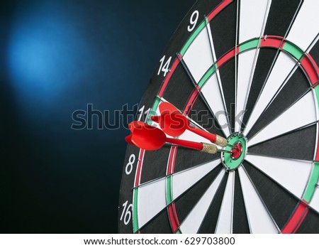 Dartboard on a black background with arrows hitting the center target