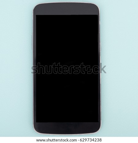 Black smart phone with blank screen lying on a table. smart phone isolated on blue background