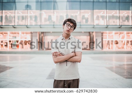 Young asian boy posing on the street without technology devices. Wearing a polo and wide pants. Man with arms crossed