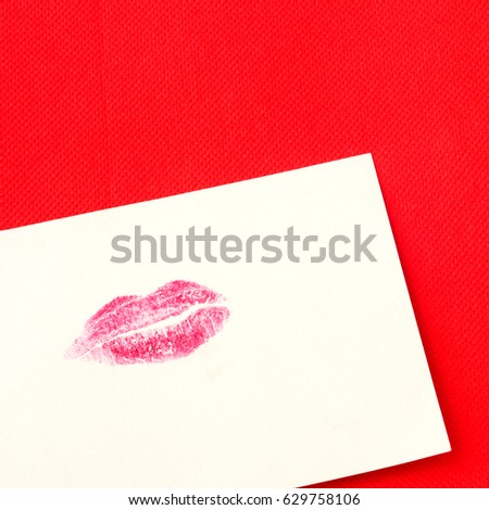 Card with red lips imprint on red background, square