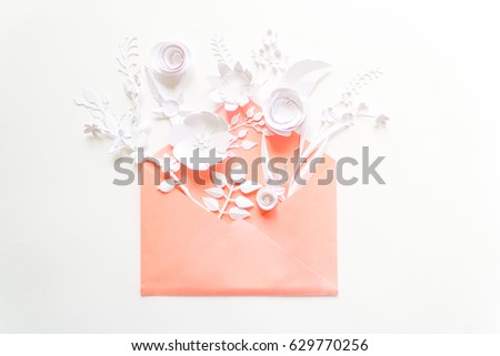 opened pink envelope full of varios white paper flowers on white background. Flat lay. Love concept.