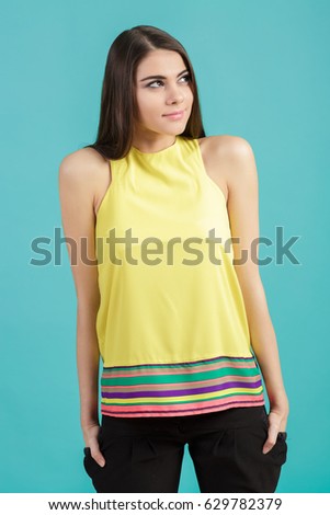 portrait of young beautiful smiling girl in yellow shirt on blue background.
