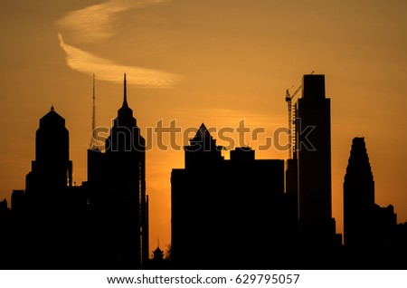 skyline in Philadelphia Pennsylvania at sunset silhouetted against a bright orange sky.