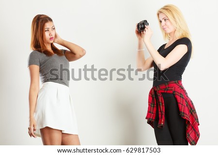 Photographer and model. Blonde girl shooting images, taking photos with camera, photographing female model