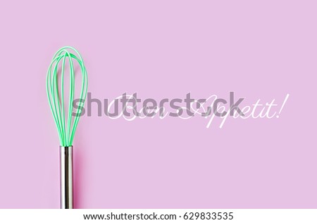 Green culinary whisk on colored background. 'Bon Appetit' - enjoy your meal quote. Creative thinking ideas, cooking concept  