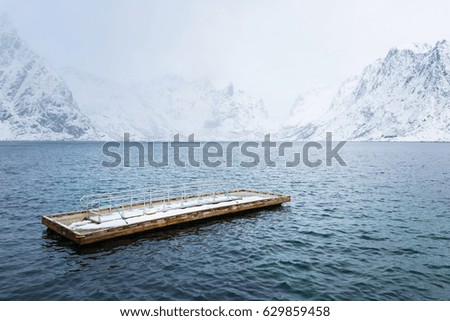 Wooden floating pier in the sea against the background of snow Lofoten mountains
