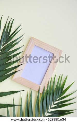 Tropical palm and leaf of monstera with frame for photo on light background. Flat lay, top view. 
