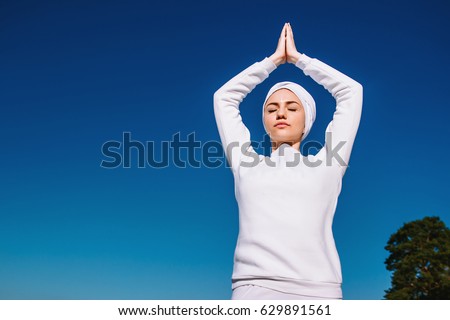 Against a background of blue sky the girl raised her hands up in a yoga pose in white clothes, kundalini, meditation
 Royalty-Free Stock Photo #629891561