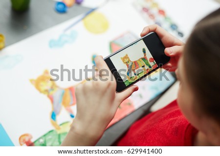 Schoolgirl photographing her painted picture for blog