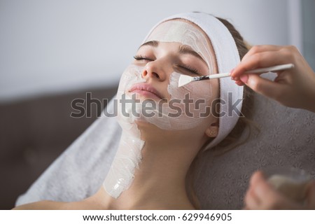 Beautician applying enzymatic peeling on woman's face in spa Royalty-Free Stock Photo #629946905