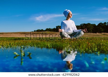 Near the water sits a yogi girl in a lotus pose and meditates on a spring sunny day
 Royalty-Free Stock Photo #629982062