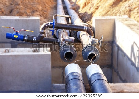 The process of installation of the distribution unit heating network. Frame for connecting pipes in the trench of sand. Royalty-Free Stock Photo #629995385