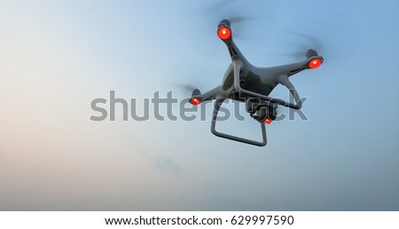 Drone with camera flies in the blue evening sky.