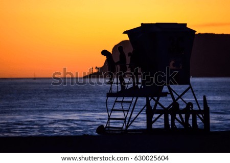 Sunset on Coronado island with silhouettes of people on lifeguard booth in San Diego, California