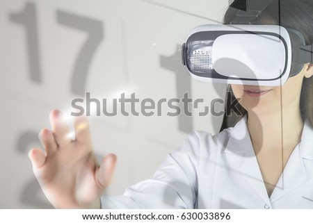 Young woman with vr headset. Woman in VR headset looking up and trying to touch calendar in virtual reality.