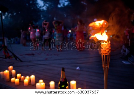 night lit torch on the beach near the water, people in the background