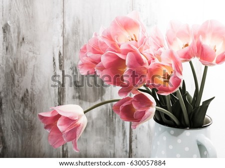 Bouquet of pink tulips in a vase on a wooden vintage wall background, with copy space for messages. Spring flowers. Greeting card for Valentine's Day, Women's day and Mother's Day.