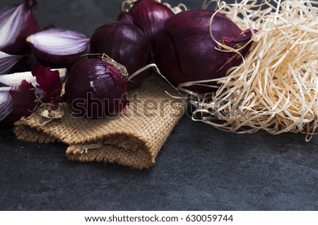 Red onion on black wooden table, moody style picture.