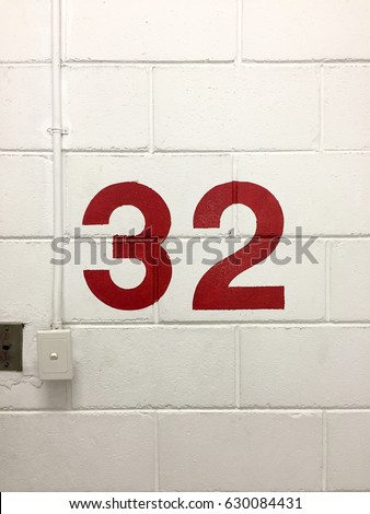 Red 32 floors level signs with light switch on the white cement brick wall